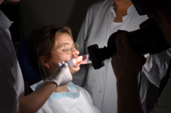 Bei einer jungen Frau wird das Gebiss fotografiert.