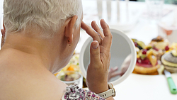 Frau von hinten blickt in den Spiegel