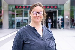 Frau mit Brille vor einem modernen Gebäude