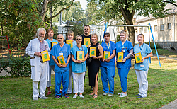 Klinikpersonal im Garten mit Buch in der hand