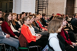 Festlich gekleidete junge Menschen sitzen in einem Podium