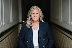 Eine Person steht in einem dunklen Gang. Sie wird hell beleuchtet.