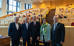 Fünf Menschen stehen mit dem Rücken zum Rang eines Hörsaals