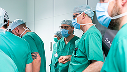 Gruppe von Personen in grüner OP-Kleidung und Mundschutz.